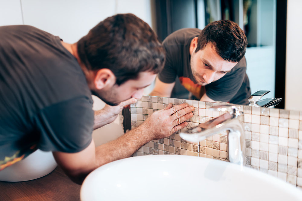 handyman or worker adding mosaic ceramic tiles on bathroom walls